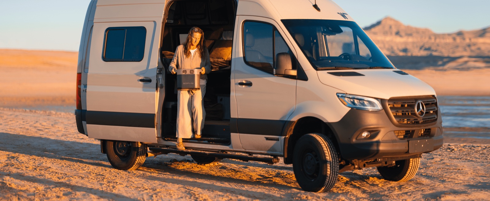 Woman carrying a power station from the door of a camper van